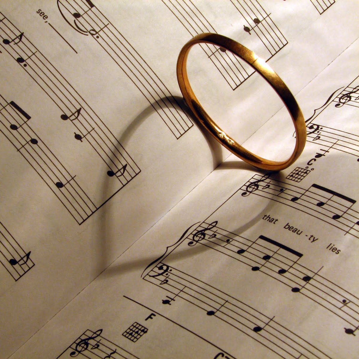 Wedding ring making heart shaped shadow on sheet music.